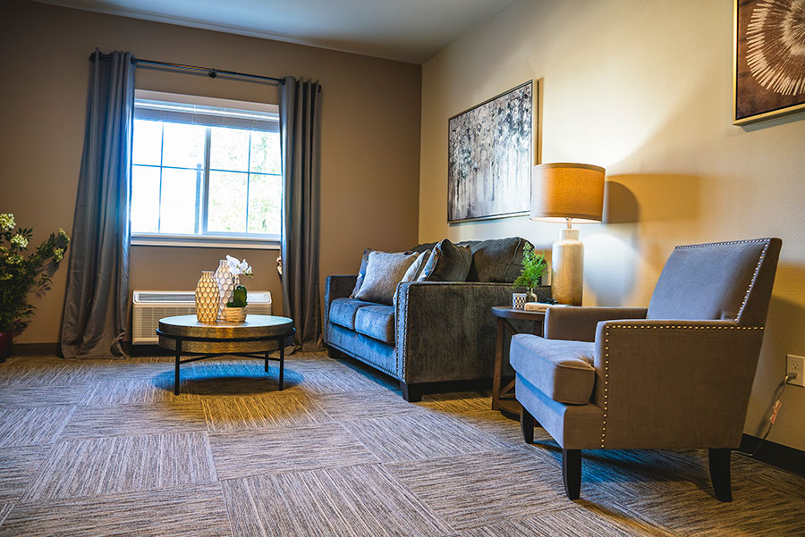 Cozy living room with window, sofa, armchair, and decor.